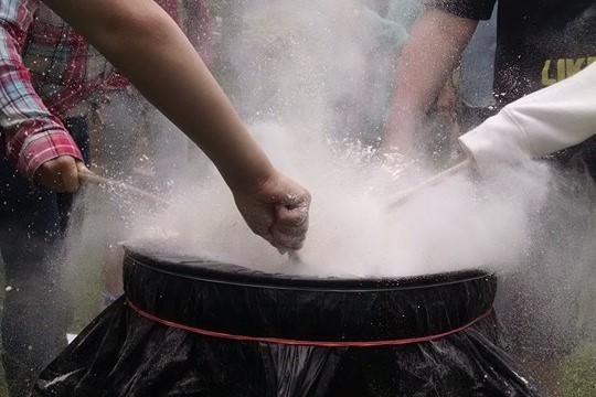 A group of kids experiment with flour and a drum.